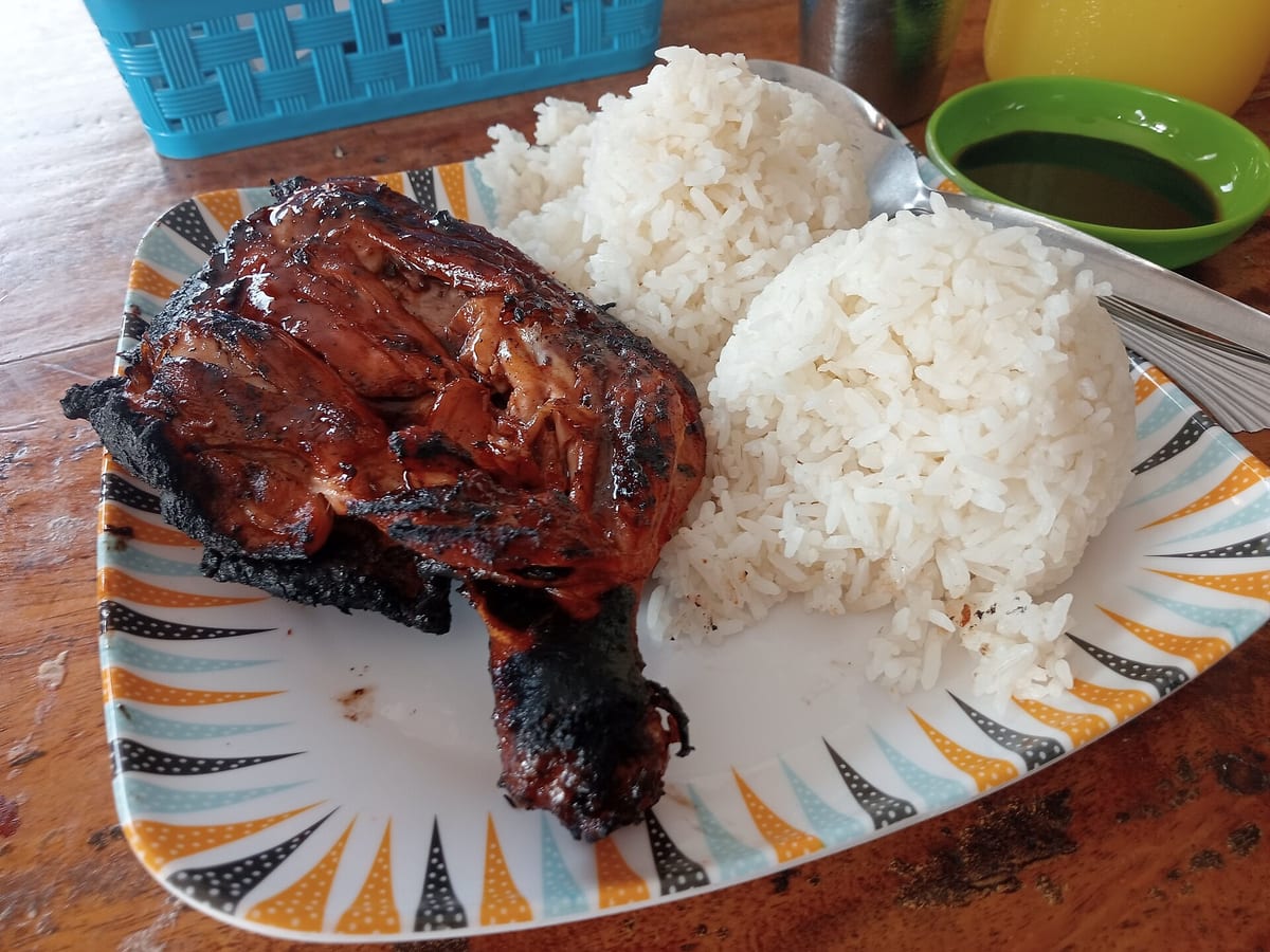 Grilled chicken inasal leg quarter with two scoops of rice and a dipping sauce