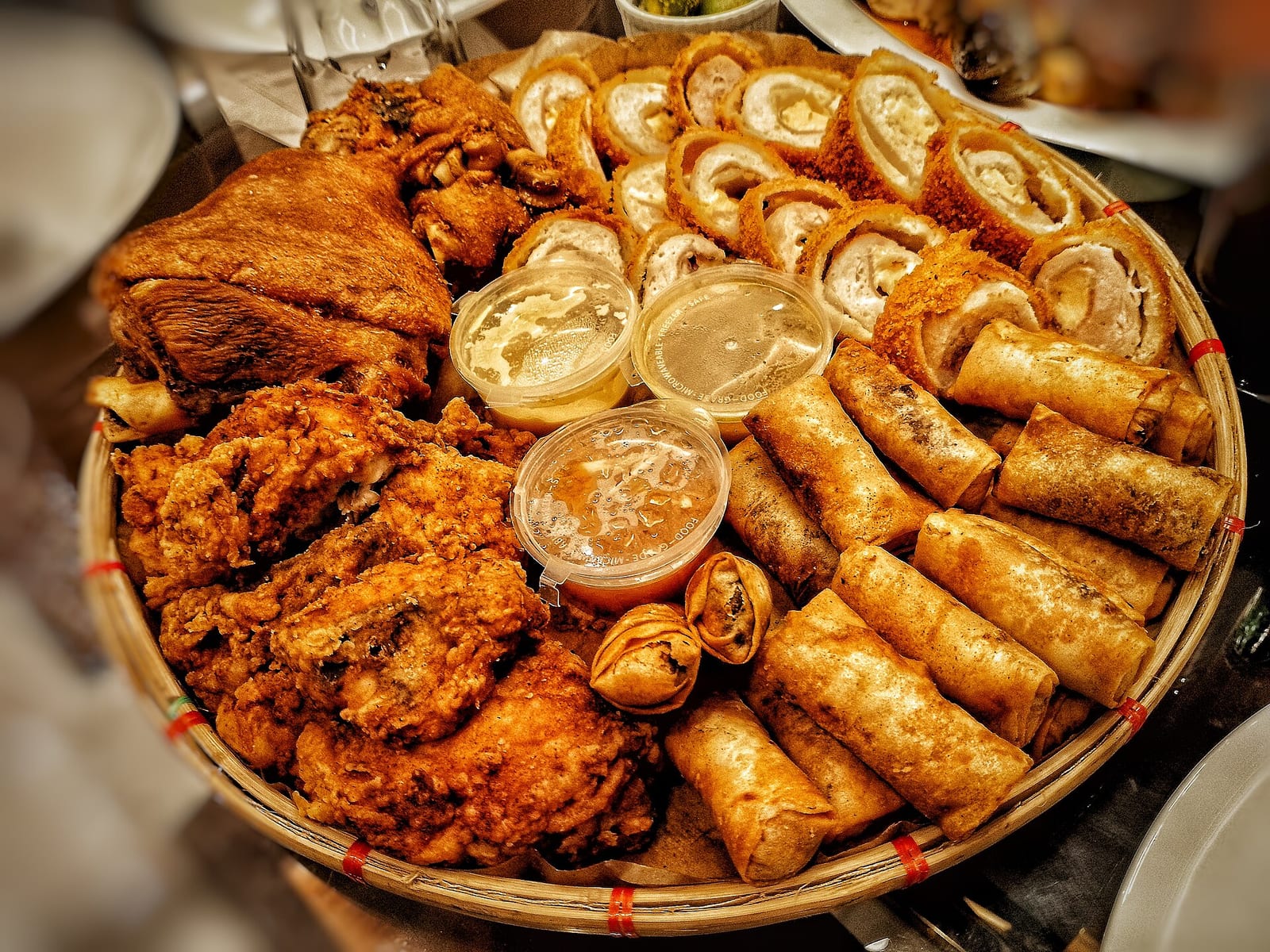 A woven bilao platter piled with crispy pork, fried chicken and golden lumpia for sharing
