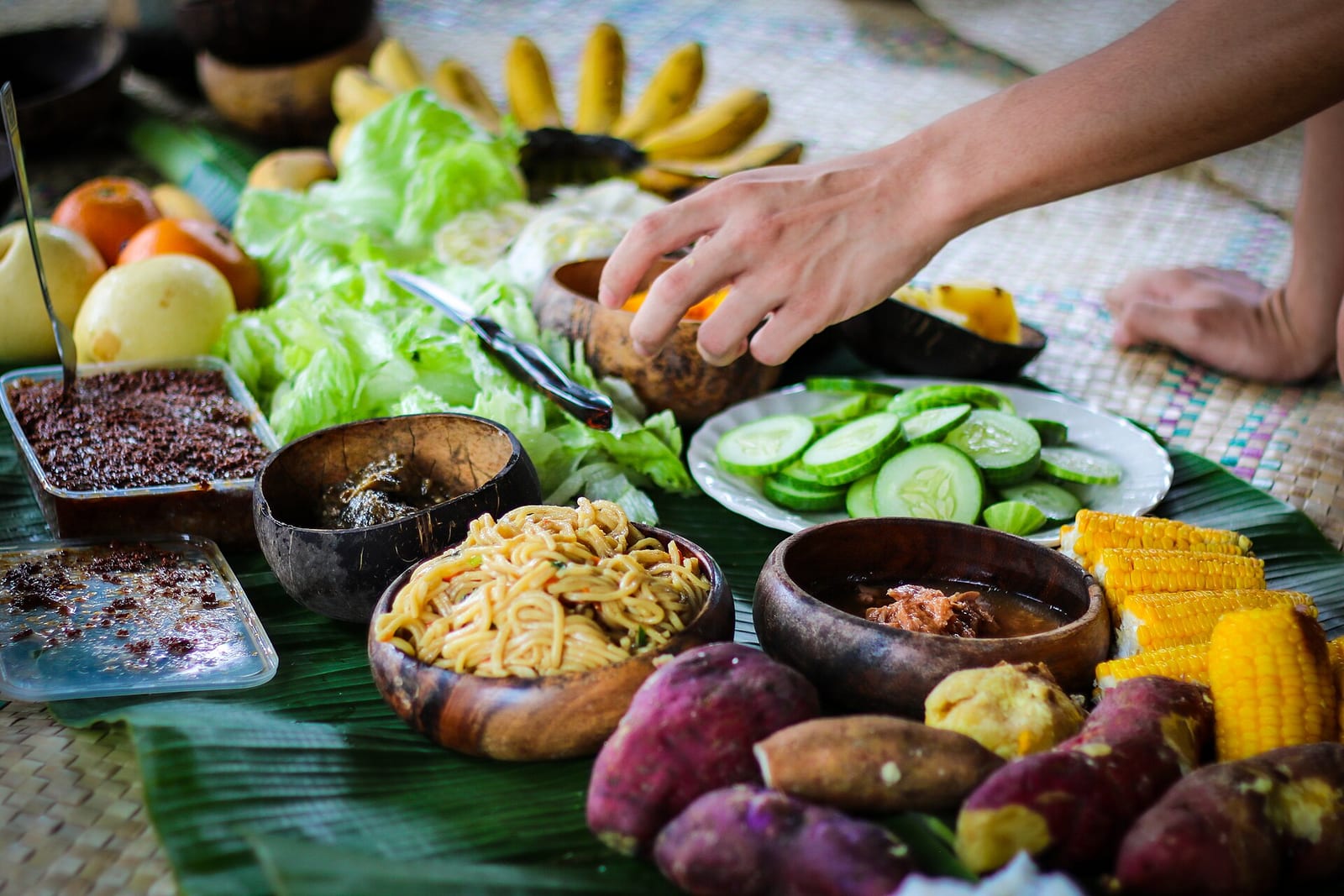 Fresh vegetables, fruit and root crops laid out on banana leaves